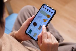 close-up-hand-browsing-shopping-fashion-mobile-app-on-sofa-at-home-e1696735545447.jpg